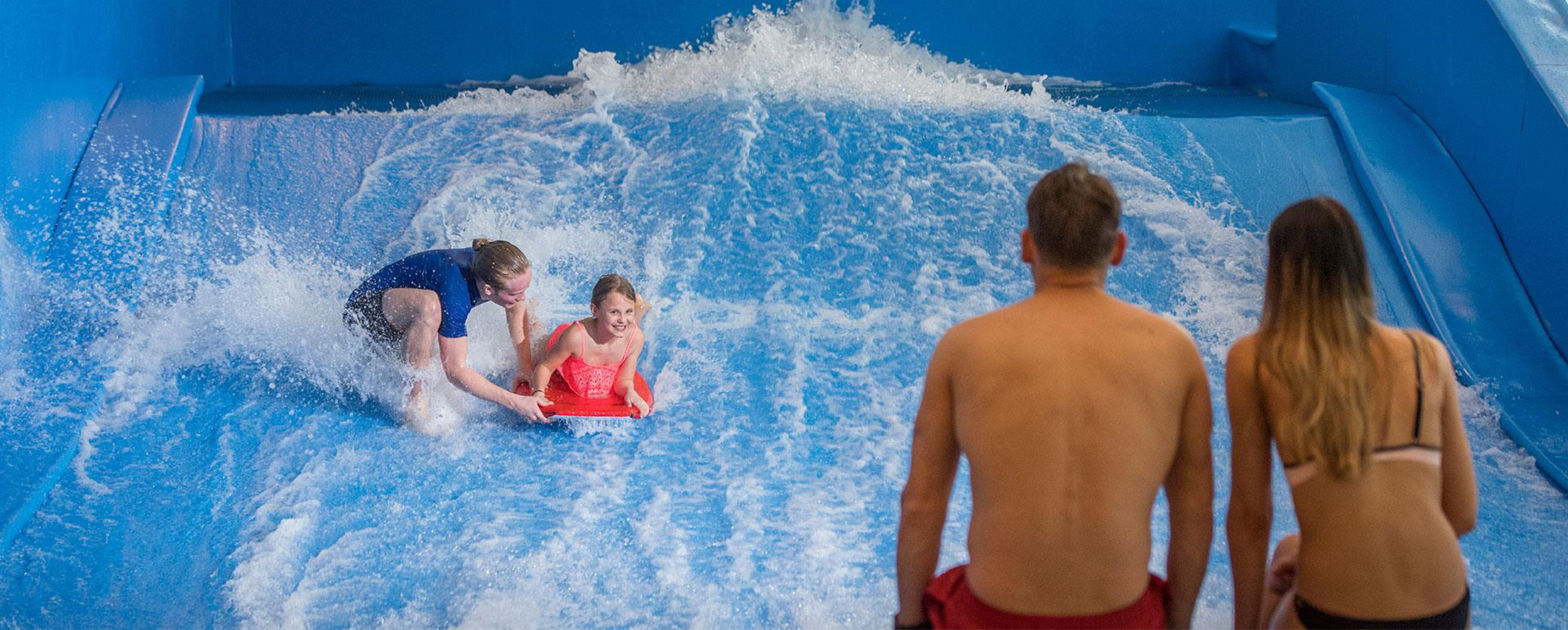 Bilde av et par som ser på barnet surfe innendørs på radisson blu i Trysil